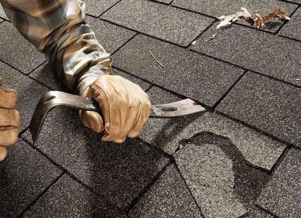 Repairing shingles on a roof with a crowbar