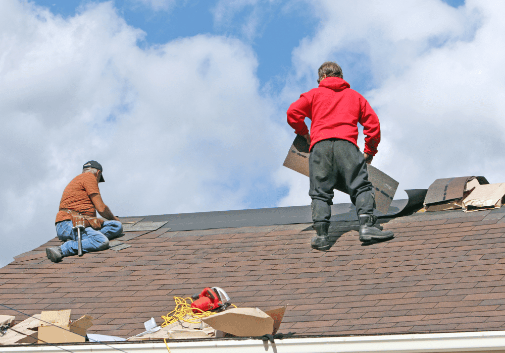 Two Licensed Roofers Installing Shingles On Roof
